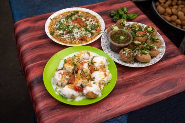 Spicy Chotpoti, plain or Doi Fuchka, pan puri, or gol gappa filled with herbs with spicy water served in plate isolated on wooden table side view of bangladeshi street food clipart