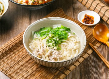 Acı biber soslu hardallı erişte, taze soğan, ahşap kaşık ve yemek çubukları Tayvan yemeklerinin yanında servis edilir.