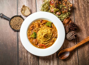 Tahta masadaki Tayvan fasyiyecek manzarasında brokoli, kaşık ve çatalla servis edilen körili tavuk çorbası.