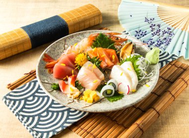 Dory sashimi, somon balığı, ton balığı ve kılıçbalığı ile çeşitli kapsamlı Sashimi tabakta servis edilir. Peçete tarafında Japon yemeğinin ahşap arka planında servis edilir.