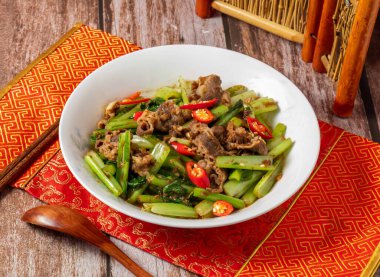 Sebze, yemek çubuğu ve kaşıkla servis edilen Shacha Lamb, Tayvan yemeğinin ahşap masasında, peçete kenarında izole bir şekilde servis ediliyor.