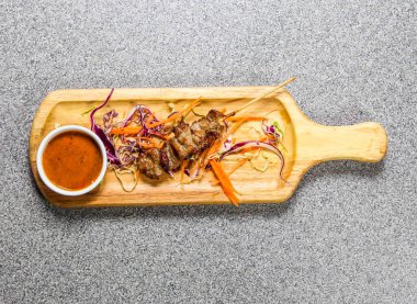 Kırmızı biber soslu domuz bbq satay, Hong Kong fast food 'un gri arka planında izole edilmiş ahşap ozanda servis edilir.