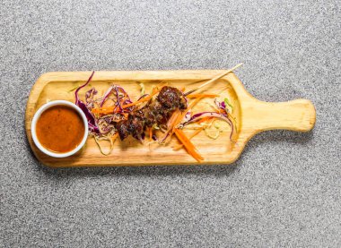 Hong Kong fast food 'un gri arka planında izole edilmiş ahşap ozanda servis edilen kırmızı biber soslu biftek bbq satay.