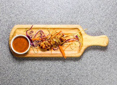 Biber soslu tavuk bbq satay Hong Kong fast food 'un gri arka planında izole edilmiş ahşap ozanda servis edilir.