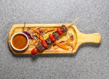 Biftek fileto, Hong Kong fast food 'un gri arka planında izole edilmiş ahşap ozana servis edilen acılı soslu satay şiş.