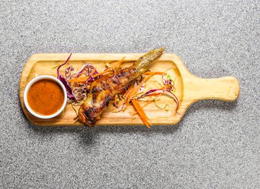 Hong Kong fast food 'un arka planında izole edilmiş ahşap ozanda servis edilen kırmızı biber soslu tavuk kanadı bbq.