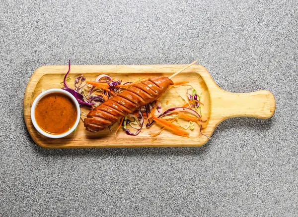 Biber soslu jumbo sosis Hong Kong fast food 'un gri arka planında izole edilmiş ahşap ozan üzerinde servis edilir.