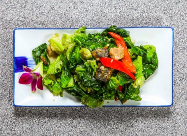 Tayland usulü kızarmış Tayland lahanası, tuzlu balık, lahana ve kırmızı biber. Gri arka planda izole edilmiş tepside servis ediliyor. Hong Kong sağlıklı yeşil yiyecek.