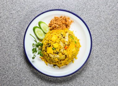 Hong Kong fast food 'un gri arka planında servis edilen tavuklu ananas pilavı ve salatalıklı kişniş.