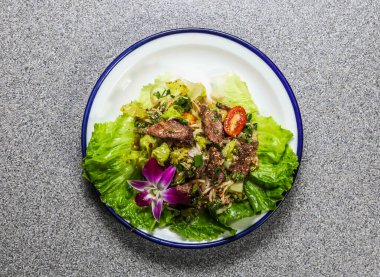 Baharatlı Biftek Kısa Pirzola Salatası, marul yaprağı, salatalık ve kişniş Hong Kong fast food 'un gri arka planında servis edilen tabakta servis ediliyor.