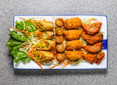 Thai snacks platter with deep fried spring roll, cheese sticks and kabab served in tray isolated on grey background top view of hong kong fast food clipart