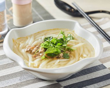 Çin yemeğinin peçete tarafından izole edilmiş kase içinde servis edilen kişniş soslu gümüş iğneli erişte seti veya kişniş tozu.