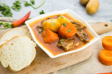 Biftek, patates, havuç, kişniş, kırmızı biber ve ekmek ile pişirilmiş ve tahtadan yapılmış tahtadan yapılmış Hong Kong yemeğinin yanında servis edilen biftek.