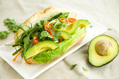 Avokado Fransız ekmeği soğanlı, havuçlu, salatalıklı ve kişniş hazır yemek masasında servis ediliyor.