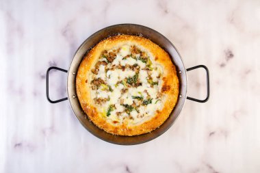 Afumicato pizza soslu, peynirli ve etli gri arka planda servis edilen İtalyan fast food manzaralı.