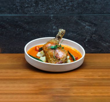 Hint usulü körili tavuk güveci, vişneli domates, patates ve yeşil biberli ve ahşap masa başında servis edilen İtalyan fast food manzarası.