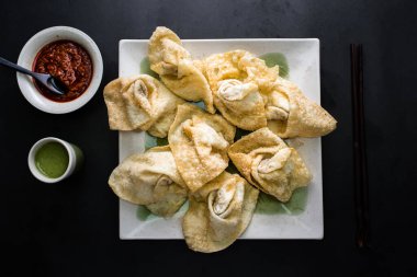 Kızarmış Wonton, yeşil ve kırmızı biberli sos. Çin yemeğinin arka planında izole bir şekilde servis ediliyor.