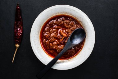 Kırmızı biber ezmesi ya da kaşık ile servis edilen sos koyu arka planda Çin yemeğinin üst görüntüsünde izole.