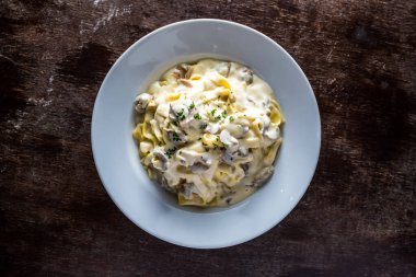 İtalyan yemeği masasında servis edilen kişniş soslu kremalı Fettuccine Alfredo makarnası.