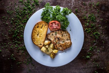 Trancio di Salmone alla Griglia ızgara somon. Kahverengi ekmek, kamış, domates ve kişniş İtalyan yemeği masasında servis ediliyor.