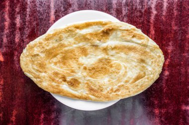 Tabakta servis edilen kızarmış Paratha veya parata Bangladeş, Hindistan ve Pakistan yemeklerini üst arkaplanda izole bir şekilde sunar.