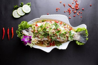 Buharda pişirilmiş kırmızı biberli ve limon soslu balık. Tayland yemeğinin arka planında izole bir şekilde servis ediliyor.