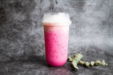 Buzlu Pembe Süt veya tek kullanımlık bardakta servis edilen çilekli milkshake gri arka planda izole edilmiş sağlıklı taze meyve suyu