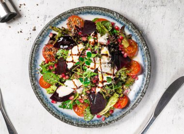 Kırmızı kinoa ve kiraz domatesli pancar peynirli salata, arka planda izole edilmiş tabakta servis edilen nar tohumları İtalyan yemeklerinin üst görüntüsü.