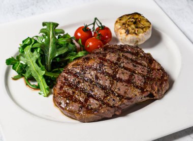 Izgara Wagyu Pirzola Bifteği ile servis edilen kiraz domatesli arka planda izole edilmiş İtalyan yemeği.