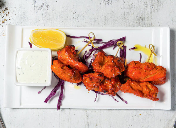 Tandoori Chicken Skewers tikka boti kabab with lemon and sauce dip served in plate isolated on background top view of italian food