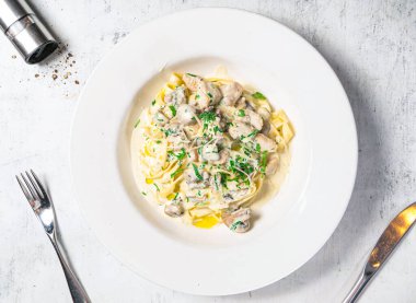 Kremalı Tavuk ya da Mantarlı Fettucini tabakta servis ediliyor. Arka planda İtalyan yemeklerinin üst görüntüsünde izole edilmiş.