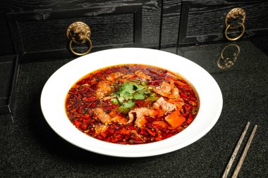 Kırmızı biberli baharatlı balık ve yemek çubuklarıyla parfüm. Arka planda koyu renk Hong Kong yemeklerinin üst görüntüsünde servis ediliyor.