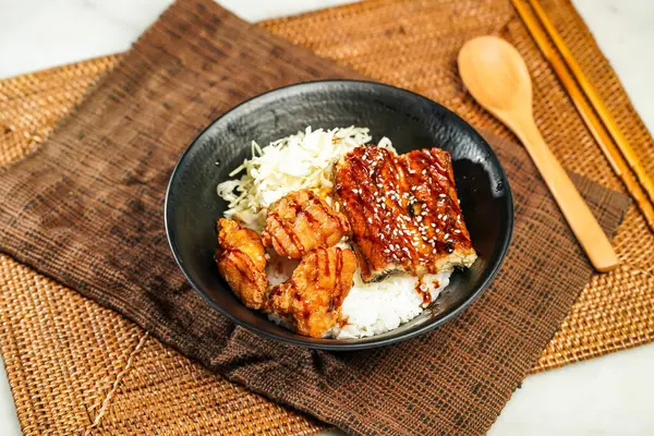 Izgara yılan balığı, bol yağda kızartılmış karides, pilav, yemek çubukları ve kaşık Japon yemeklerinin peçete tarafında izole edilmiş vaziyette servis edilir.