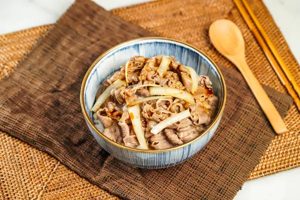 stock image UMAI Beef Donburi with chopsticks and spoon served in bowl isolated on napkin side view of Japanese food