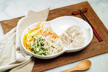 Japon usulü soğuk doğranmış tavuklu şehriye, wasabi limon soslu ve buharda pişirilmiş hamur köftesi, çubuk ve kaşık Çin yemeği peçete tarafında servis ediliyor.