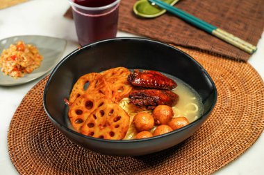 Nilüfer kökü kabı. İçecekle ve yemek çubuklarıyla servis edilmiş. Peçete tarafında Japon yemeği manzarası var.