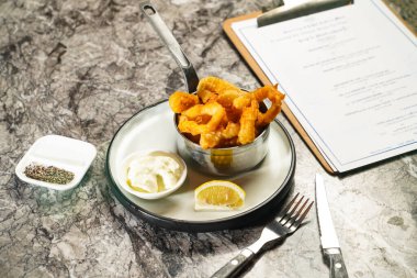 Japon Wasabi mayonez soslu, çatallı ve bıçaklı çıtır kalamar halkaları mermer arka planda Hong Kong yemeklerinin arka planında servis ediliyor.