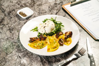 Porcini wonton, mozzarella, roket, sos, çatal ve bıçakla mermer arka planda Hong Kong yemeklerinin izole edilmiş tabaklarında servis edilir.