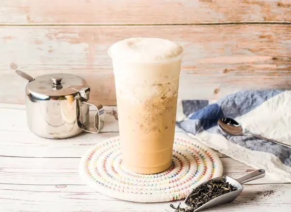 stock image Iced Tieguanyin milk tea or Tie guan yin milk tea with sugar pot and spoon served in disposable glass isolated on table side view of hong kong tea