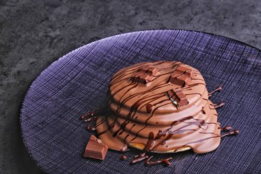 Çikolatalı krep yığını zengin çikolata sosu serpiştirilmiş ve üzeri çikolata parçacıklarıyla kaplı.