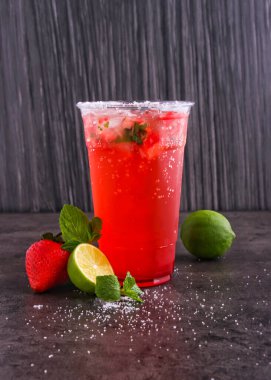 Çilek aromalı naneli mojito, limon suyu, nane yaprağı ve cam kaplama izole edilmiş koyu arka planda sunulan maden suyu.