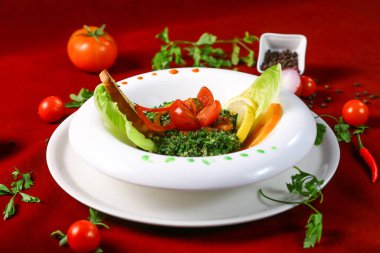 Tabbouleh salatası bulgur, domates, vsalatalık birleşimi, limon suyu ve kırmızı arka planda servis edilen zeytinyağından oluşur.