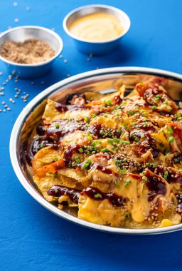 Kimçi, tavuk, peynir, sos, mayonez sosu, susam tohumu ve yeşil soğan ile dolu. Mavi arka planda izole edilmiş, sağlıksız fast food yan görüntüsü.