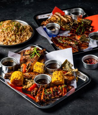 Izgara et, sarımsaklı pilav, ızgara mısır koçanı, Peri Peri Tavuğu, Jerk Chicken, Biftek göbeği, domuz göbeği ve tepside servis edilen soslar ile Filipin ziyafeti.