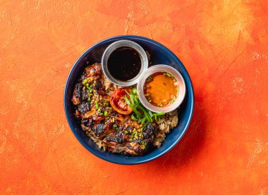 Limonçimenli ızgara Tavuk İnasal Pirinç ve sosu portakal arkaplanına izole edilmiş fast food yemeğinin üst görüntüsü.