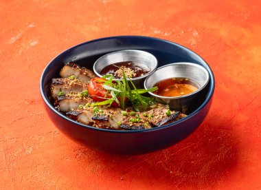 Kore usulü ızgara domuz eti kasesi, portakal arka planında izole edilmiş soslu fast food yemeği manzaralı.