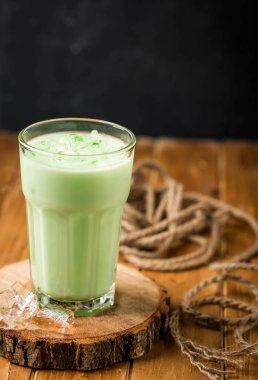 Arap yeşil şerbeti ya da şerbeti, matcha latte, üzerinde buzla servis edilen soğuk Arap içeceği ahşap masa kenarında izole edilmiş buzlar.