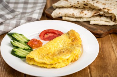 Taze sebzeli ve Pita ekmekli yumuşak omlet. Tahta masa kenarındaki Arap kahvaltısı manzarasında servis ediliyor.
