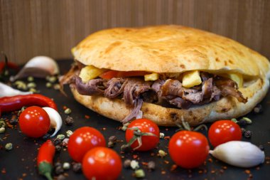 Domatesli, sarımsaklı, kırmızı biberli, domatesli Tombik Doner Kebap Sandviçi. Koyu arka planda, Türk fast food 'unun yakın plan görüntüsü.