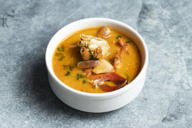 Tom Yum Deniz Ürünleri Çorbası, yengeç, karides ve Tayland yemeğinin gri arka planında yalıtılmış et suyunda servis edilen karides.